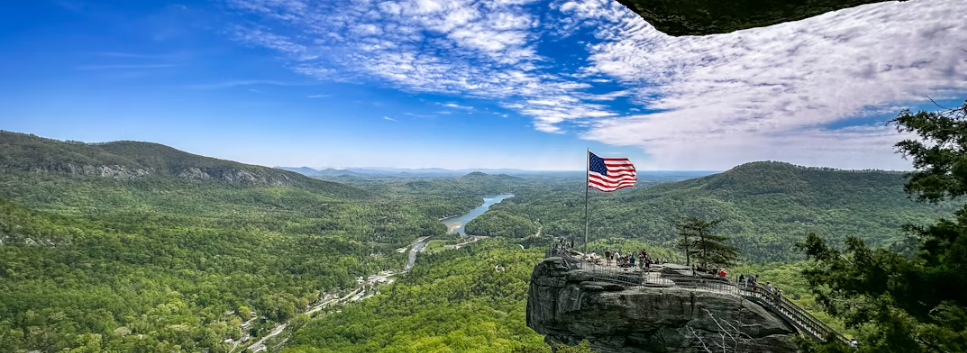 American flag waves above cliff and beautiful green scenery